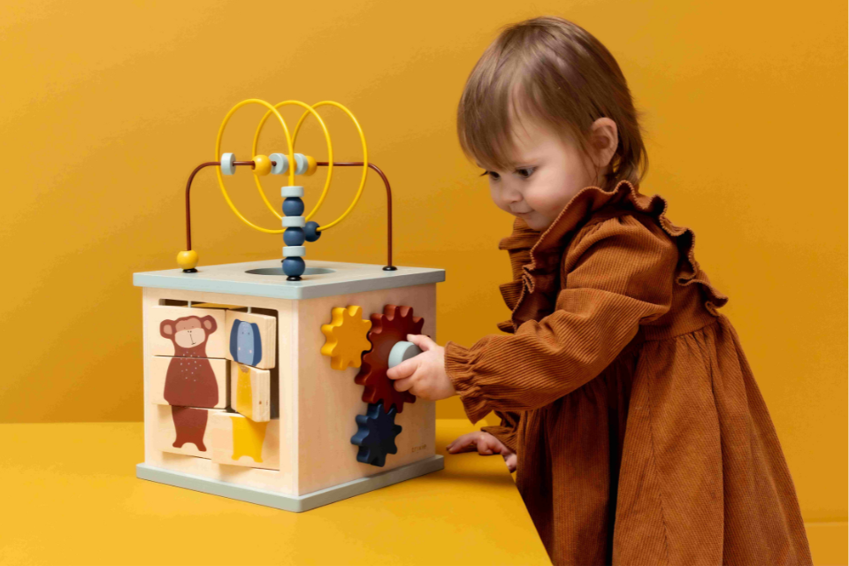 meisje dat met een houten activiteitenkubus speelt