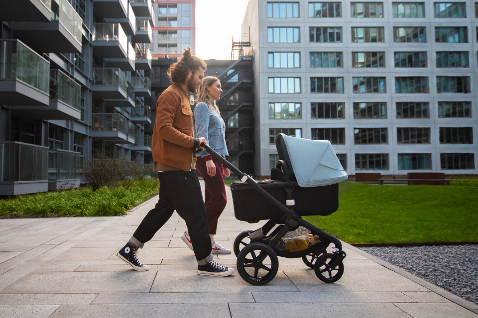 ouders wandelen met reiswieg op de kinderwagen