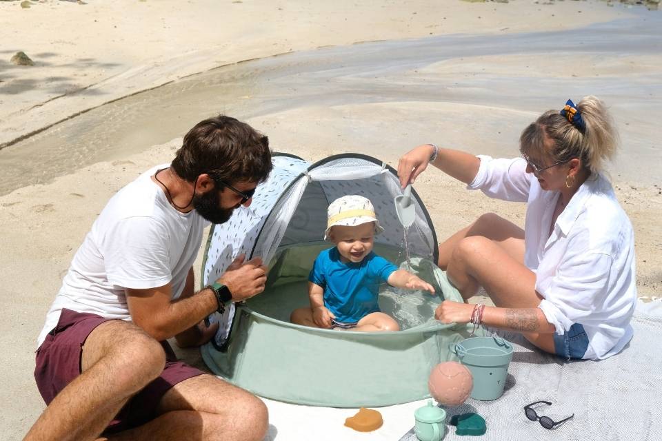 Ouders met baby op het strand en Aquani tent van Babymoov