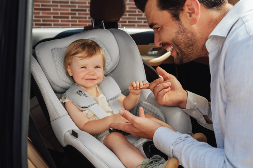baby in autostoel die vinger van papa vasthoudt