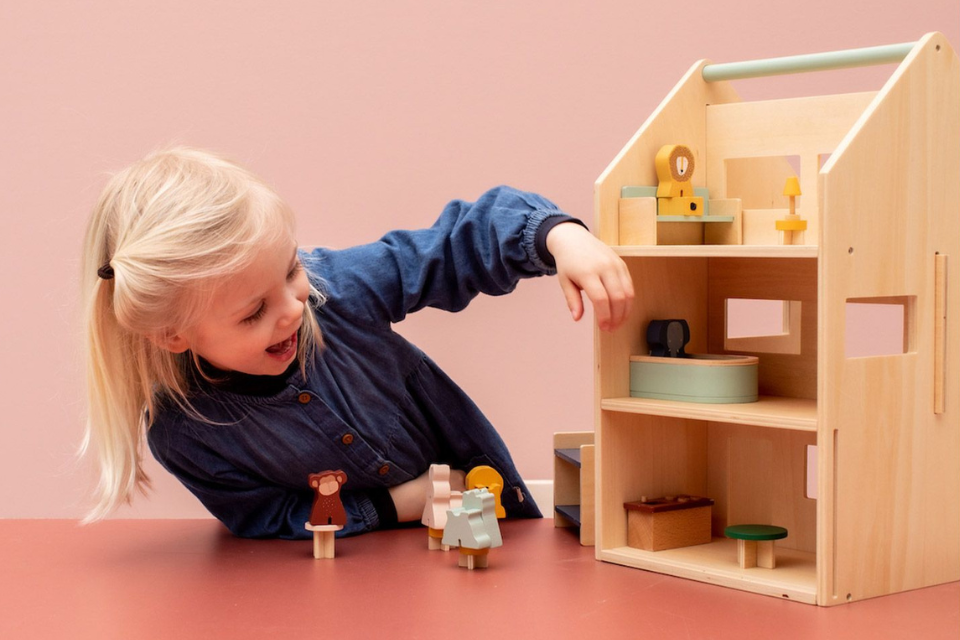 meisje dat met een houten poppenhuis speelt