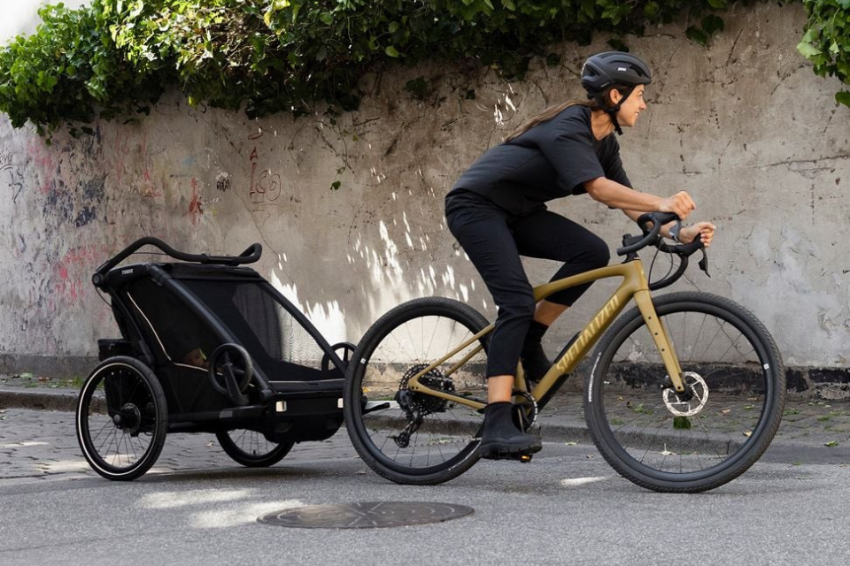 vrouw op een fiets met een fietskar achteraan
