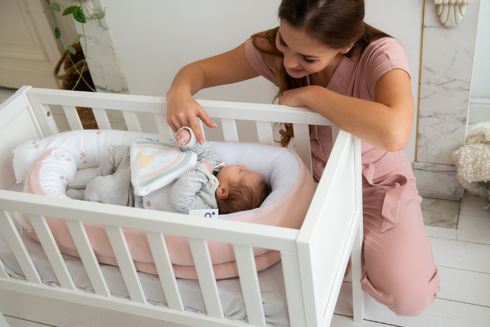 vrouw met baby in wieg