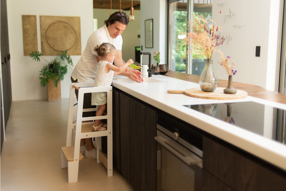 meisje in de keuken op een leertoren met papa naast haar