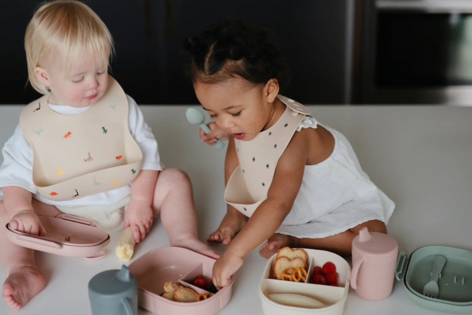 twee kindjes met slabbetjes en eten