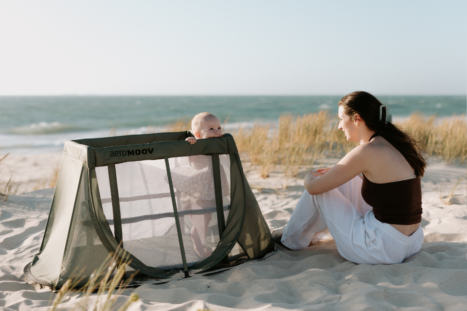 mama en baby in reisbed aan het strand