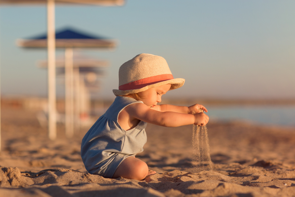 baby die in het zand speelt