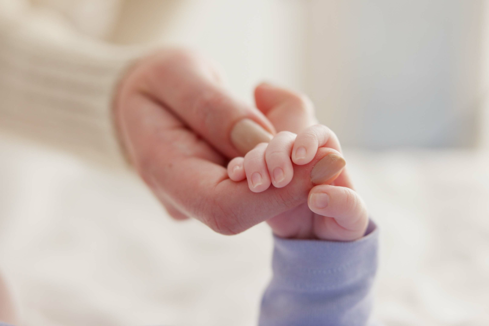 mama die babyvingers vasthoudt